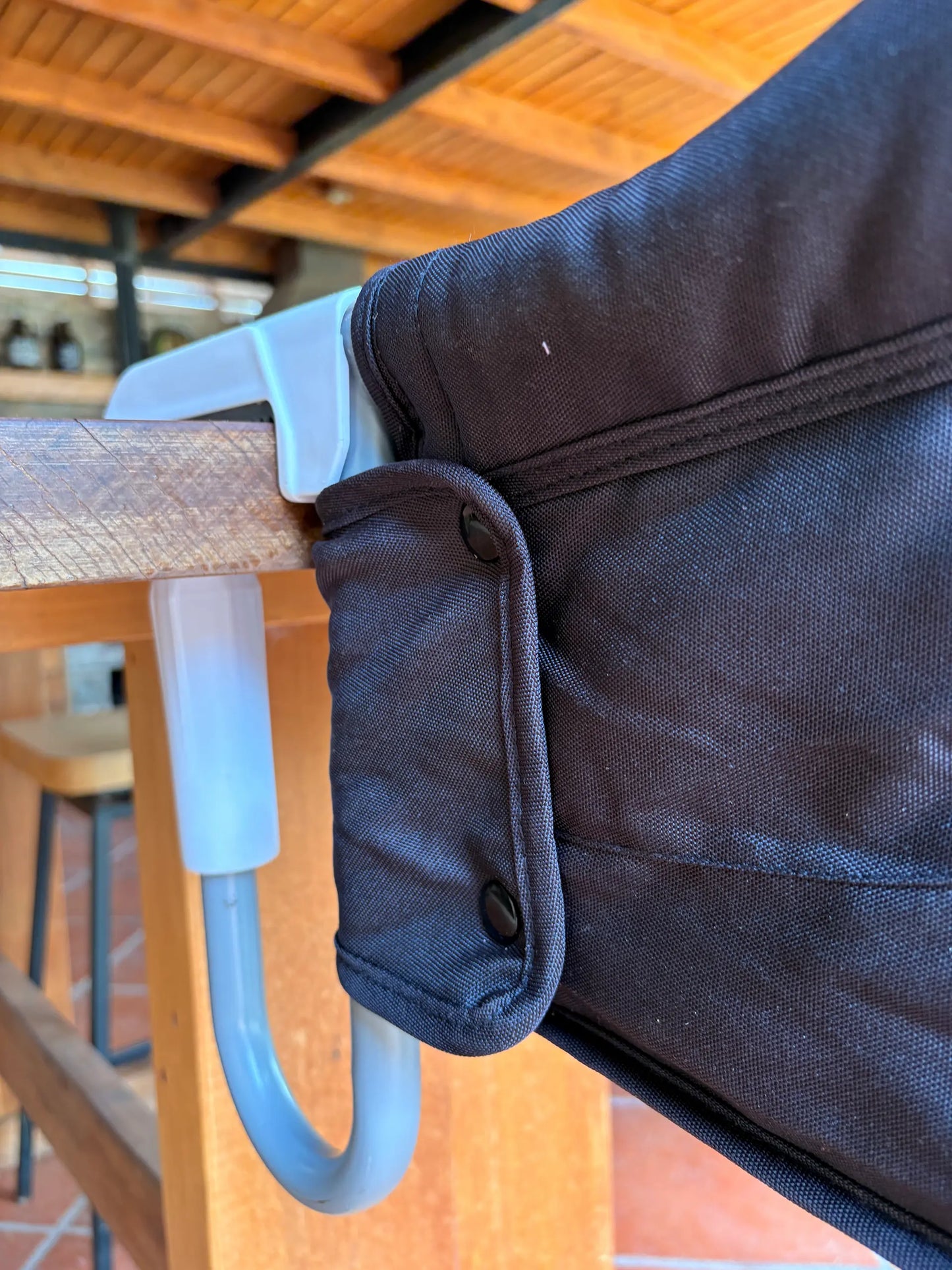 Silla HookOn azul instalada en mesa exterior - silla portátil para bebé MemoKoala