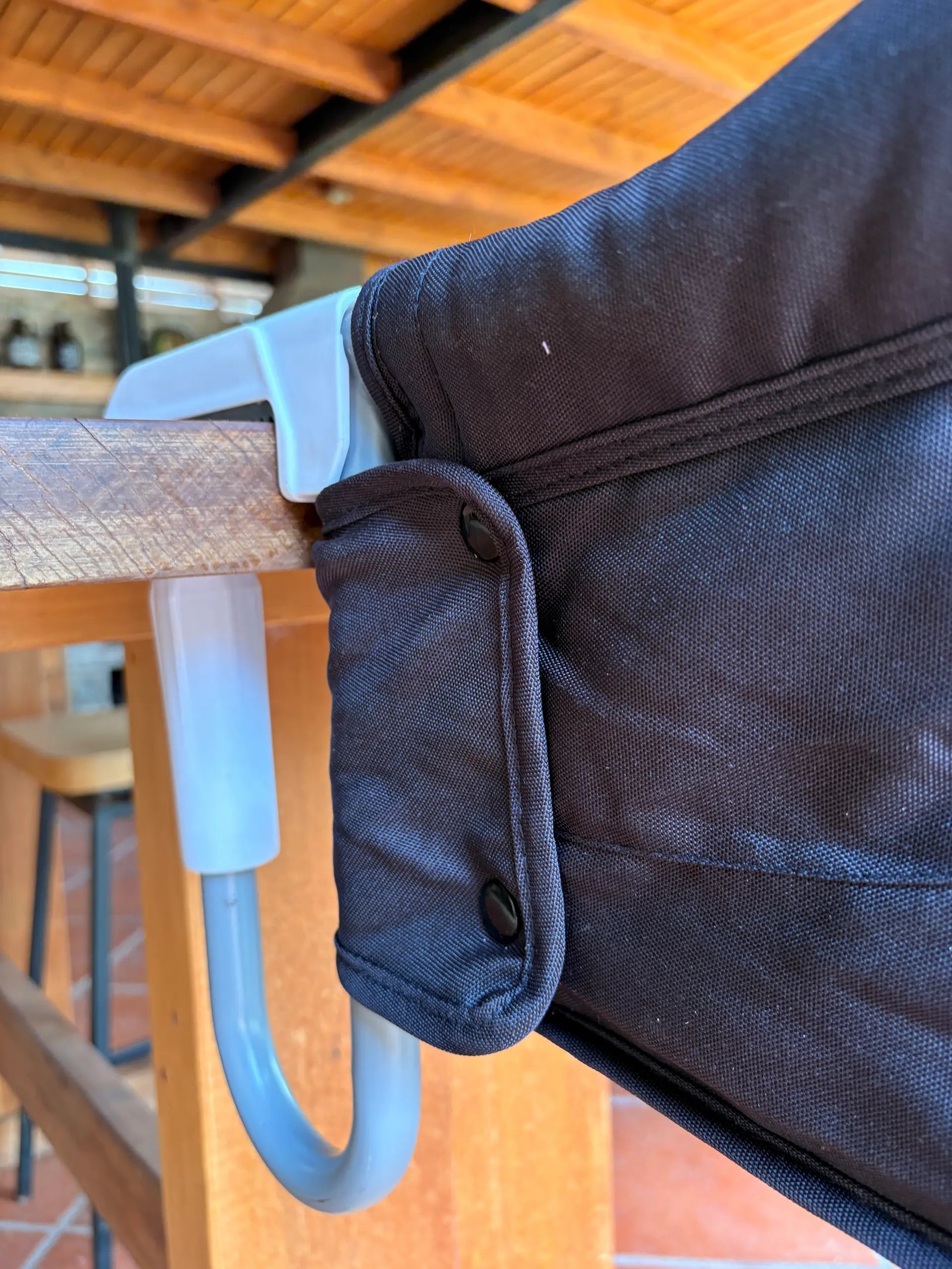 Silla HookOn azul instalada en mesa exterior - silla portátil para bebé MemoKoala