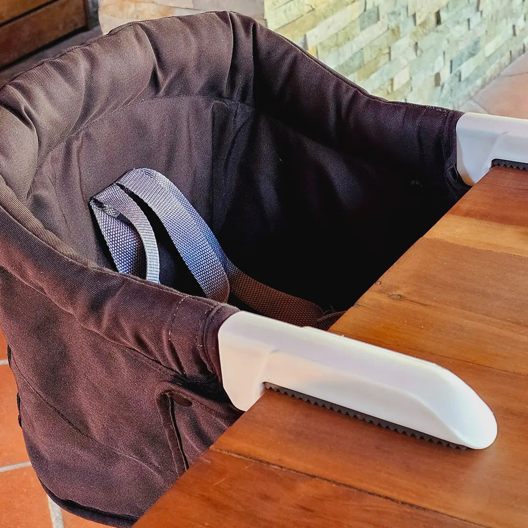 Silla portátil HookOn negra MemoKoala instalada en mesa con ganchos visibles - para bebés 6 meses a 3 años